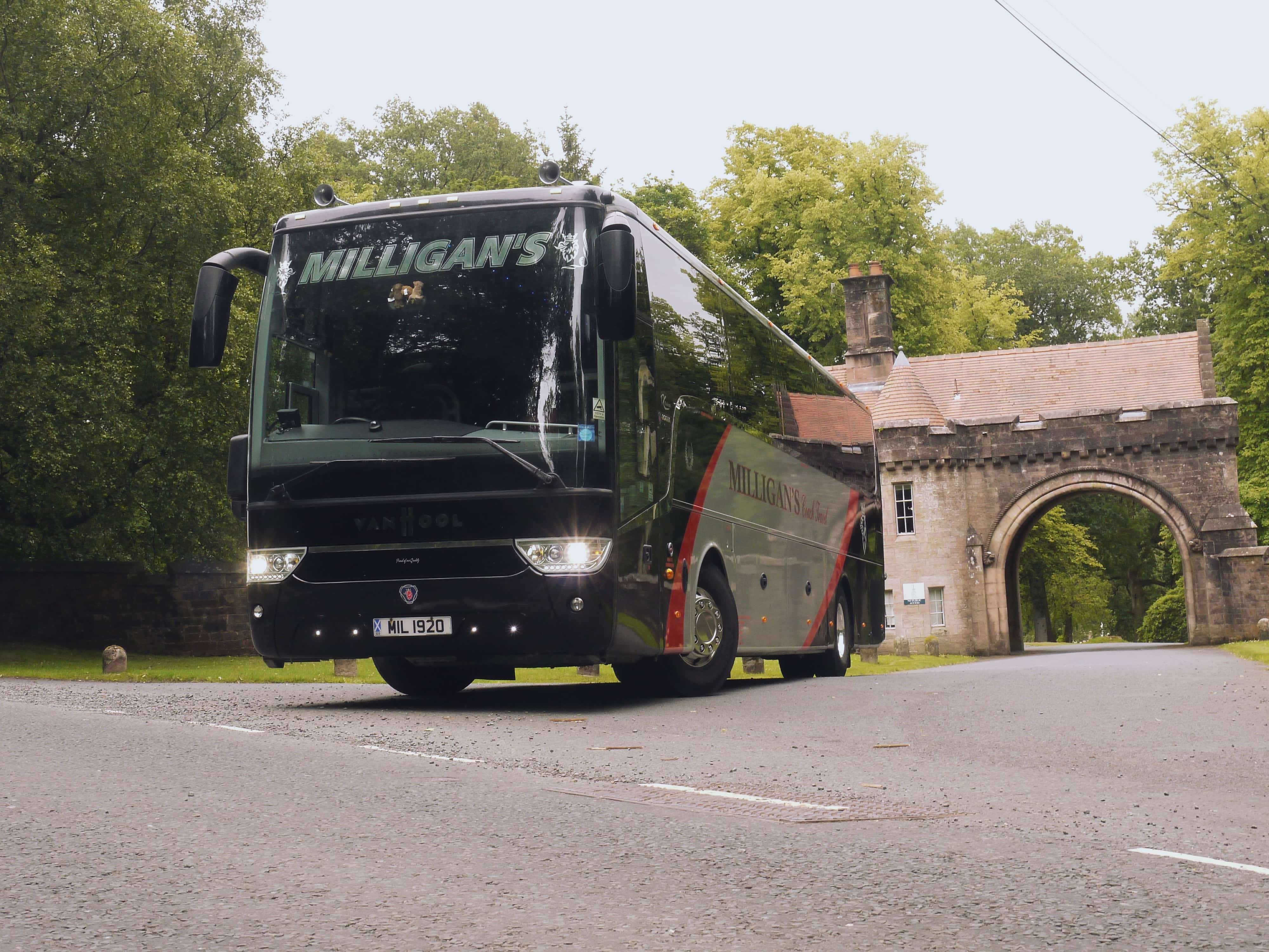 Photo shows a Milligan's branded coach parked in front of an archway.